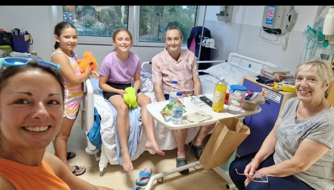 John Alexander sat on a bed in hospital, with his family.