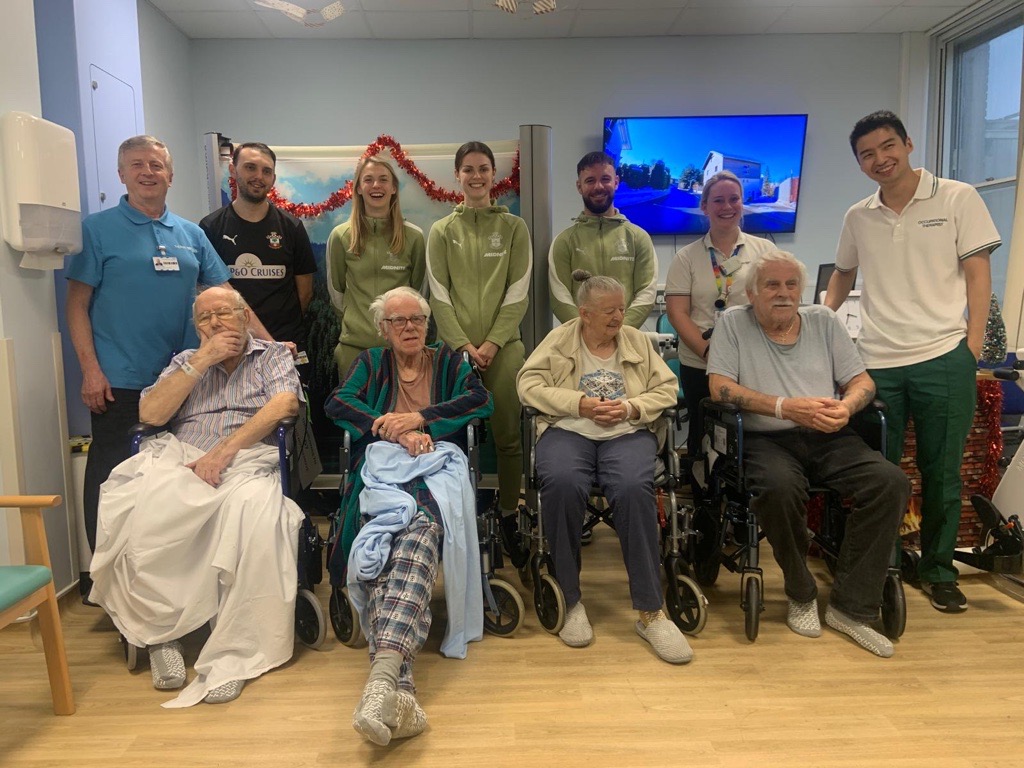 Four patients sat with Saints players standing behind.