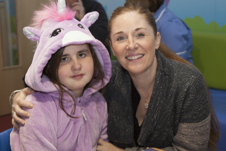 A mum sat with her arm around her daughter.