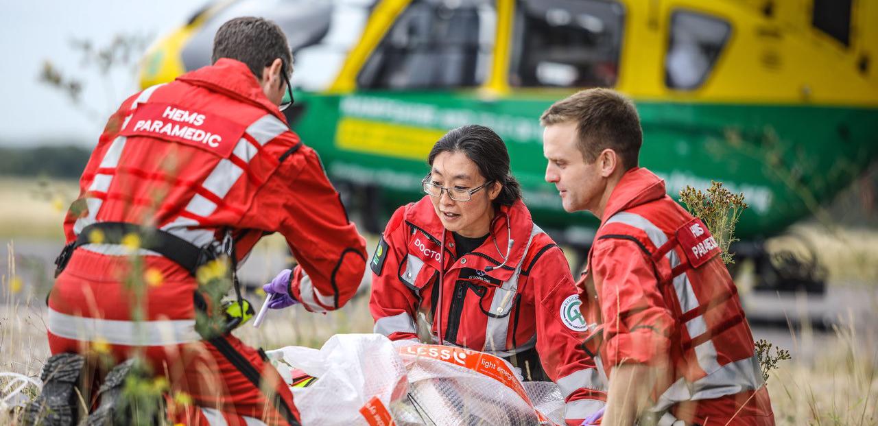 Paramedics and a doctor care for a patient next to an air ambulance