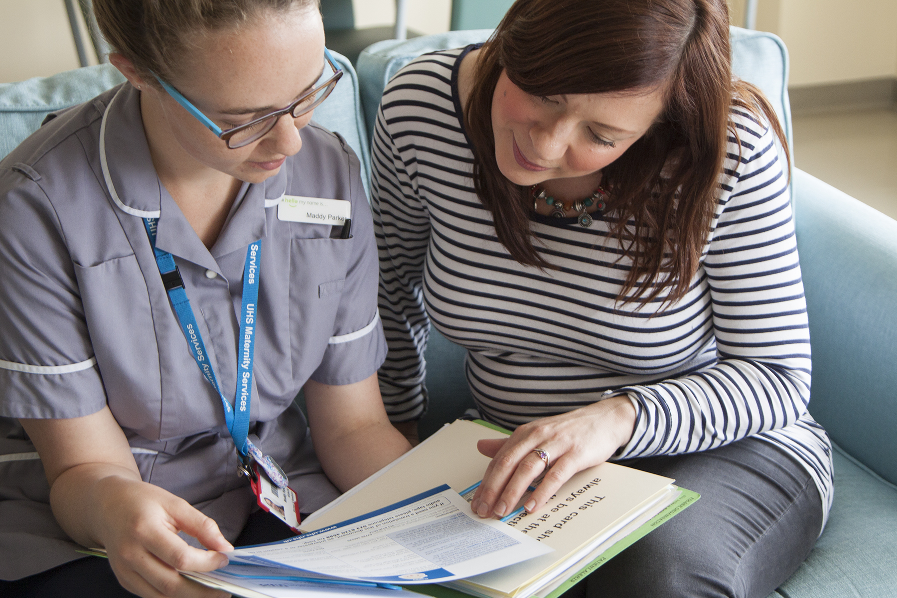 A member of staff and pregnant woman looking at an information sheet