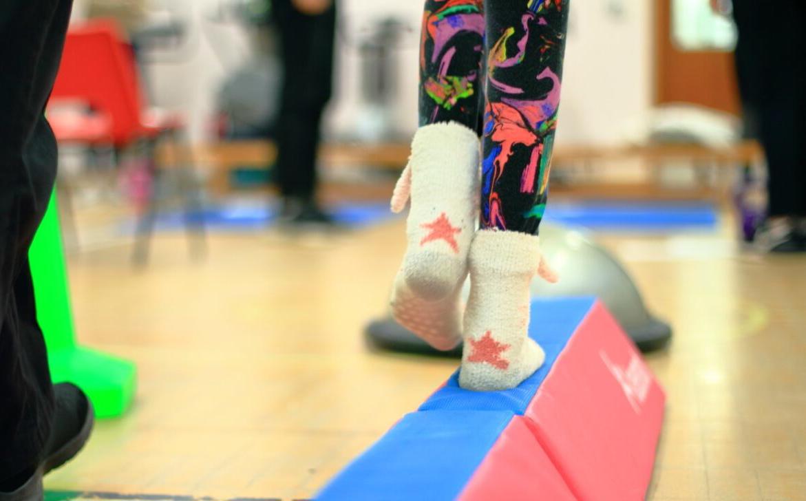 Child's feet as they walk along a soft beam