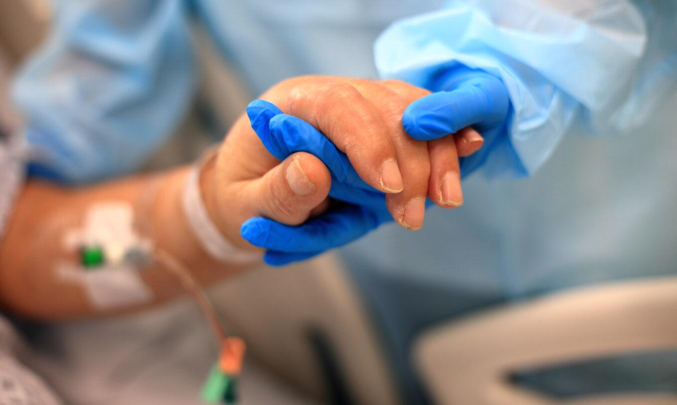 Member of staff holding a patient's hand in GICU