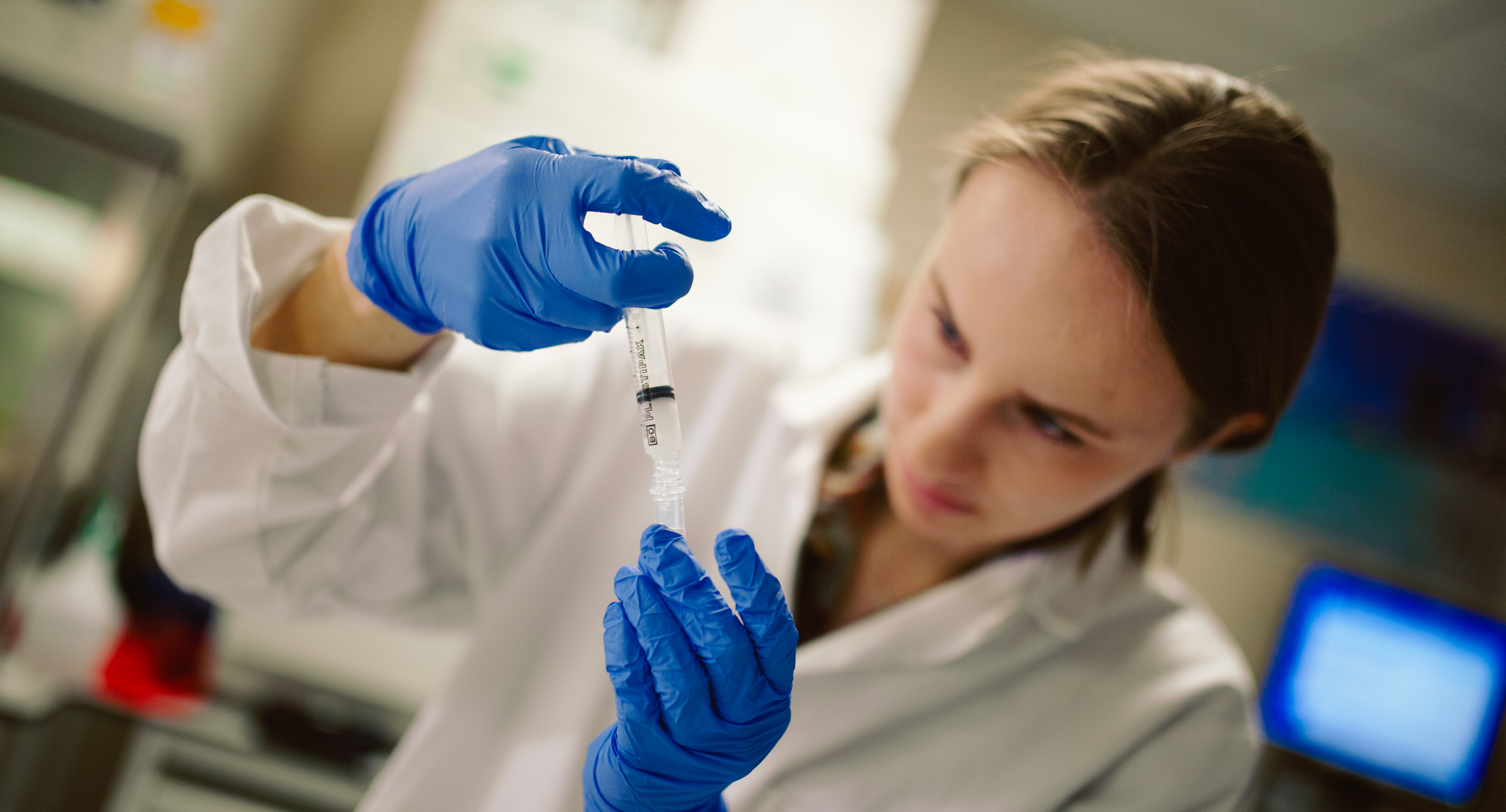 A clinical research nurse looking at a vial of liquid